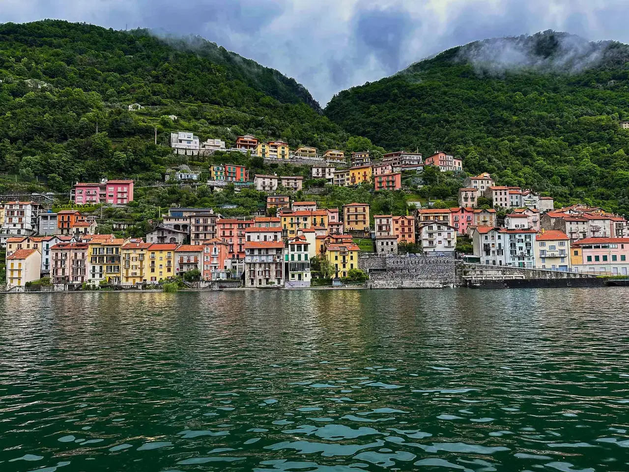 Lakefront buildings beneath forested hills