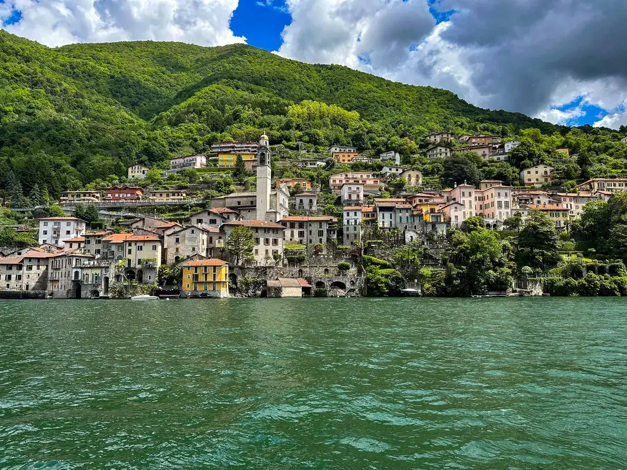 A village on a green hillside above the lake