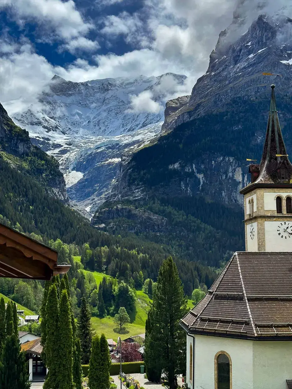 Green alpine slopes beneath snow-capped peaks