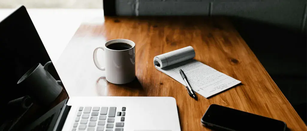 Work desk with laptop, coffee mug, notes and smartphone